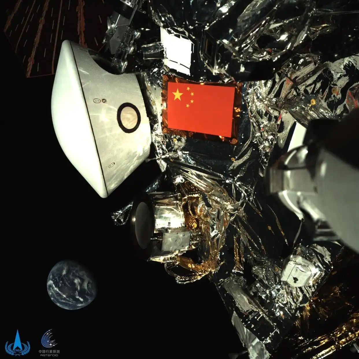 China’s Tianwen‑2 spacecraft has released a new image showing the probe, its return capsule, and the Chinese flag with Earth in the background, captured by a robotic arm camera during its journey. The China National Space Administration confirmed the probe is operating normally, about 43 million kilometers/26.5 million miles from Earth, after completing in‑orbit tests including deployment of sampling devices. Tianwen‑2 is en route to near‑Earth asteroid Kamoʻoalewa (classified as one of Earth’s seven quasi‑moons, with evidence suggesting it may be debris originating from the Moon), where it will attempt sample collection in 2026 for return in 2027. After releasing the return capsule with the sample, the spacecraft itself will continue on an extended journey to study 311P/PANSTARRS, a main‑belt comet known for its unusual multiple dust tails. China conducts much of its space activity outside U.S. partnerships, as the 2011 Wolf Amendment bars NASA and other agencies from bilateral cooperation with Chinese entities. At the same time, China has worked with partners such as the UAE and ESA on the Tianwen‑1 Mars mission and has signed agreements with countries including Russia, Pakistan, South Africa, Venezuela, and the UAE to join its planned International Lunar Research Station (ILRS). 