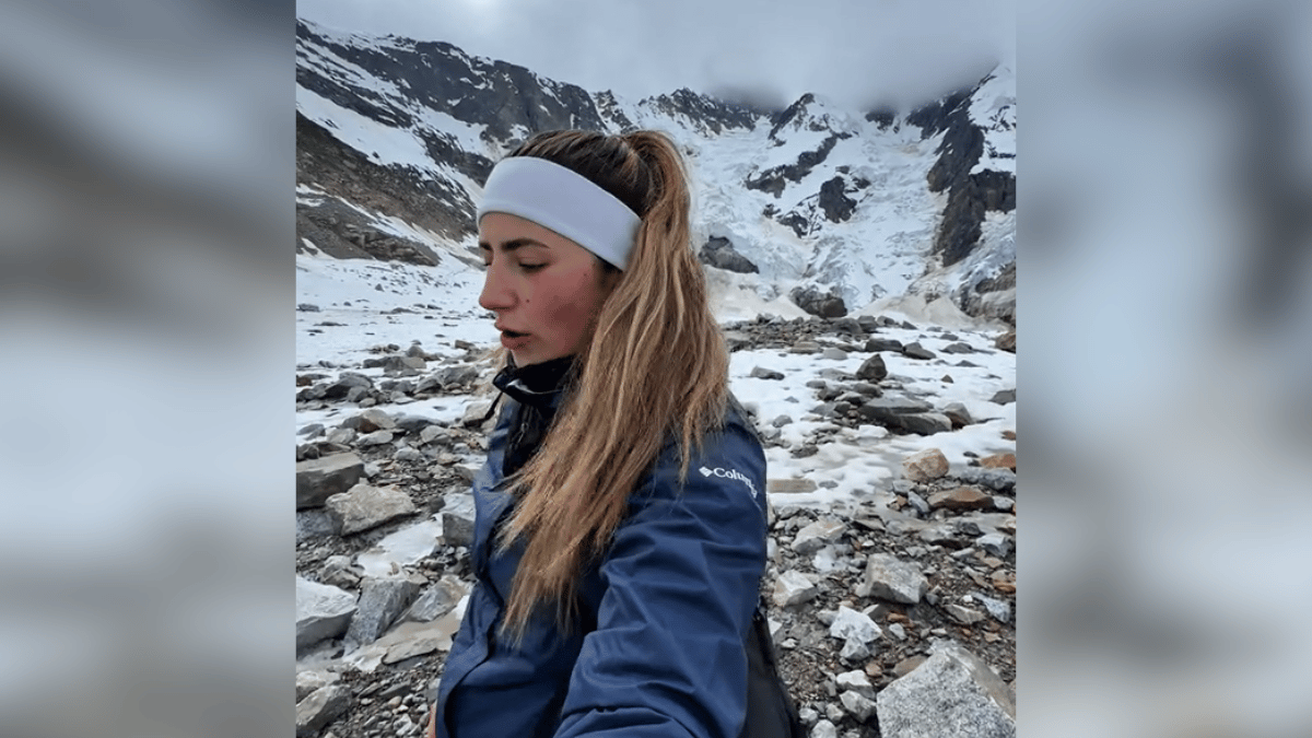 A woman hiking to a glacier in Alaska with snowy mountains in the background.