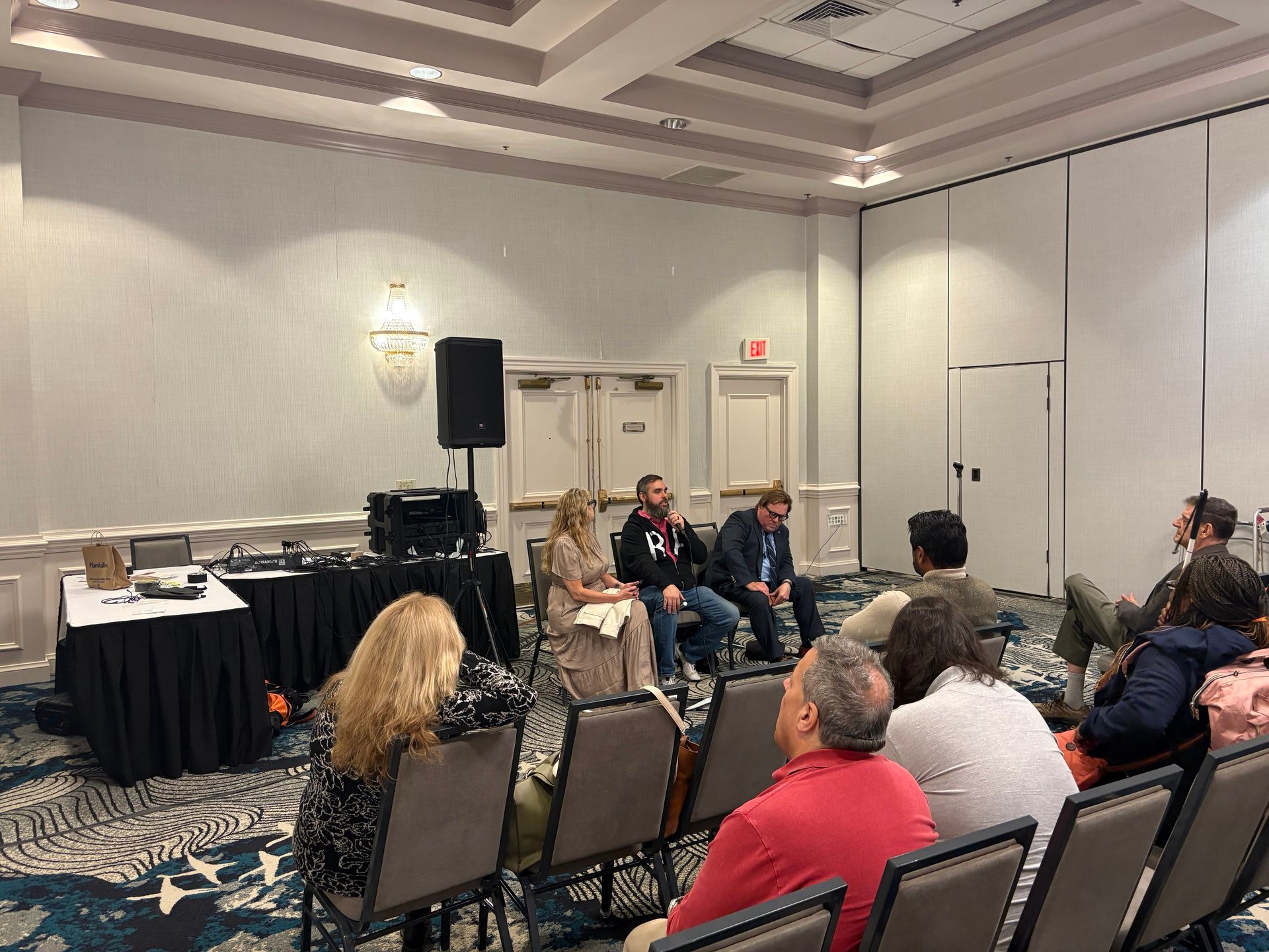 Bryan and two panelists seated at the front of a conference room speaking to attendees about wearable assistive technology.