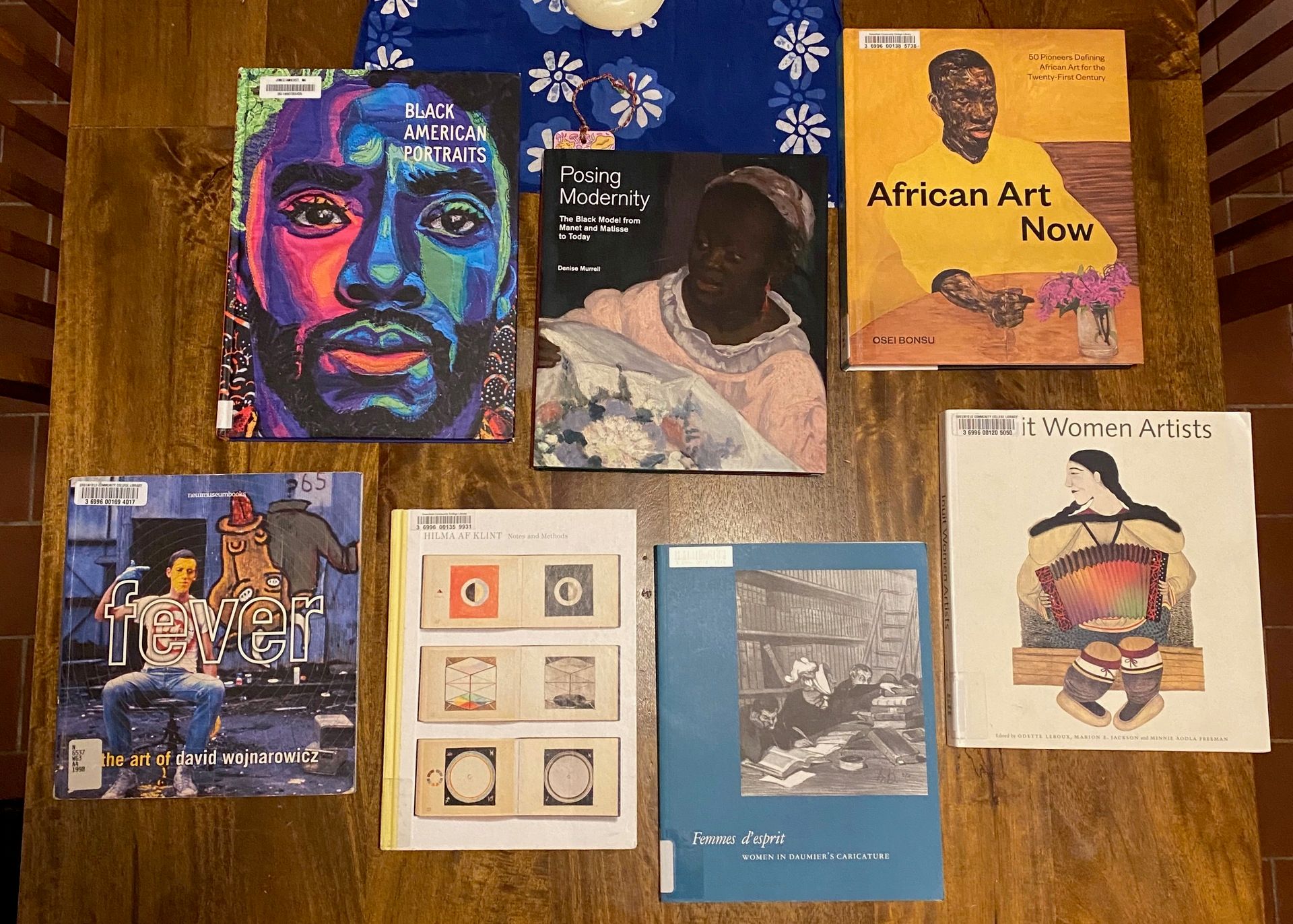 Seven of the art books mentioned above lying flat on a wooden table.