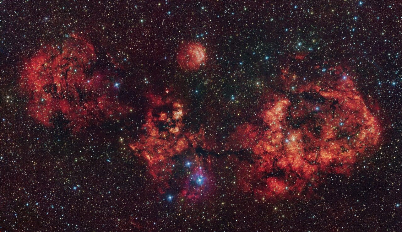 ESO’s Paranal Observatory has released a composite image of RCW 94 and RCW 95, two H II regions in the Milky Way, revealing a vast emission nebula shaped like a bat—dubbed the “Cosmic Bat” for its Halloween-timed release. Captured using the VLT Survey Telescope and VISTA, the image combines visible and infrared data to show hydrogen gas ionized by young stars. RCW 94 forms the bat’s right wing, while RCW 95 outlines its body. The structure highlights active star formation and the complex interplay of radiation and dust. Astronomers note the image’s value in tracing stellar feedback and nebular morphology.