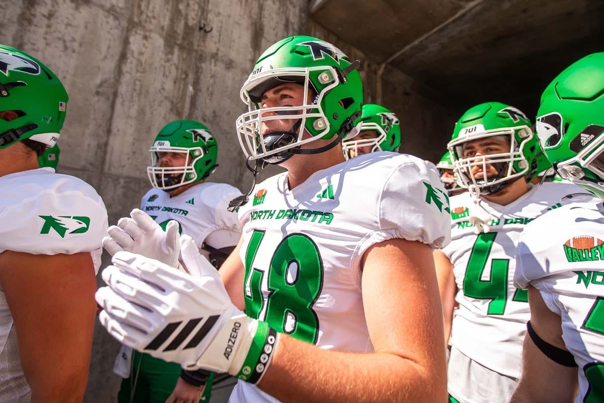 Menomonie's Brody Thornton gets ready to go out onto the field for his University of North Dakota team. The Fighting Hawks are wearing white uniforms with green numbers and green helmets. 