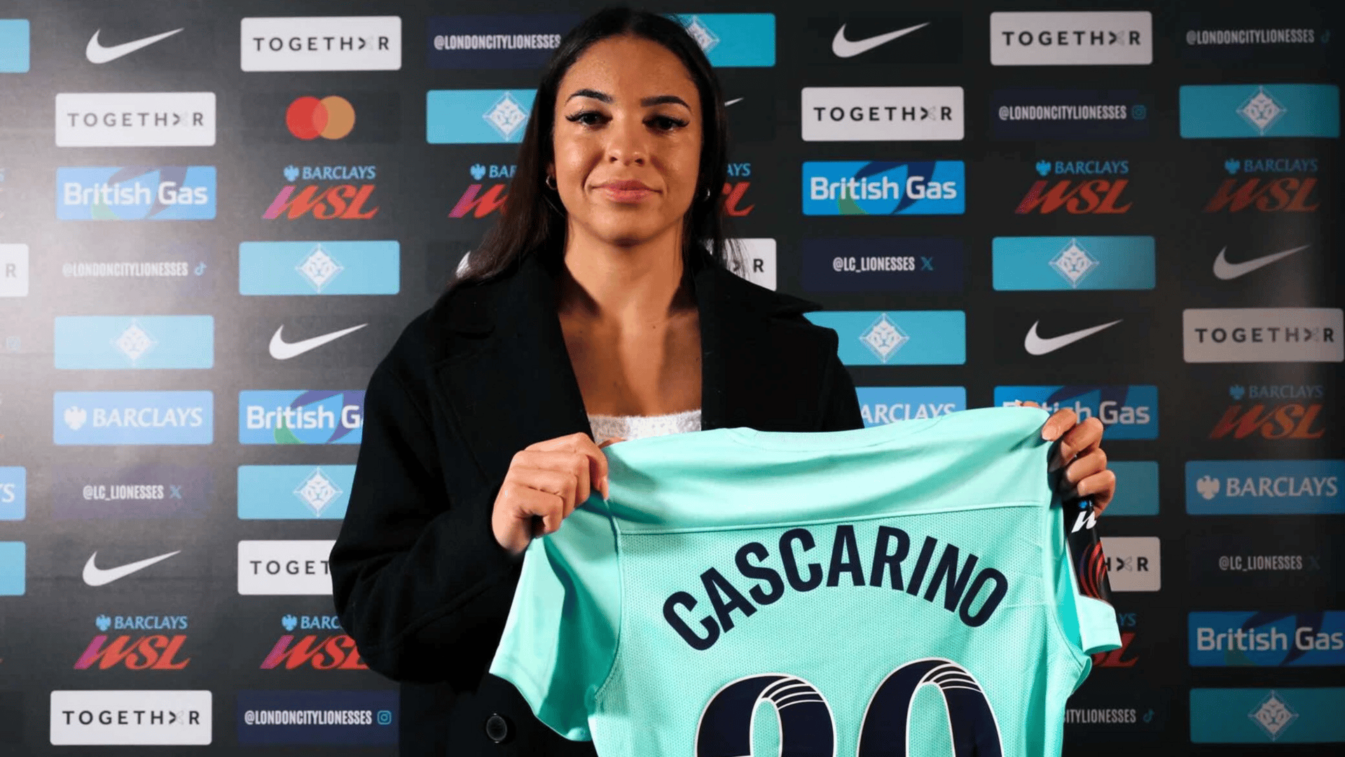 Delphine Cascarino holds a London City Lionesses jersey against a WSL mixed zone backdrop.