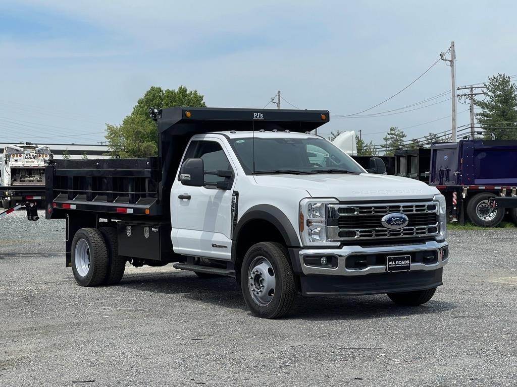 White Ford F-550 dump truck with steel body parked at a dealership lot — an example of a standard dump upfit suitable for general use but not ideal for municipal snow and ice applications.