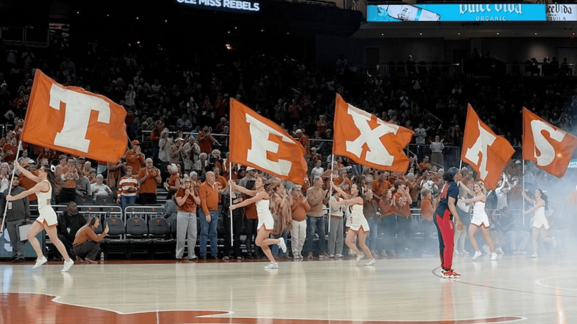 Texas Longhorns cheerleaders carry flags on to the court ahead of players before a game against the Ole Miss Running Rebels