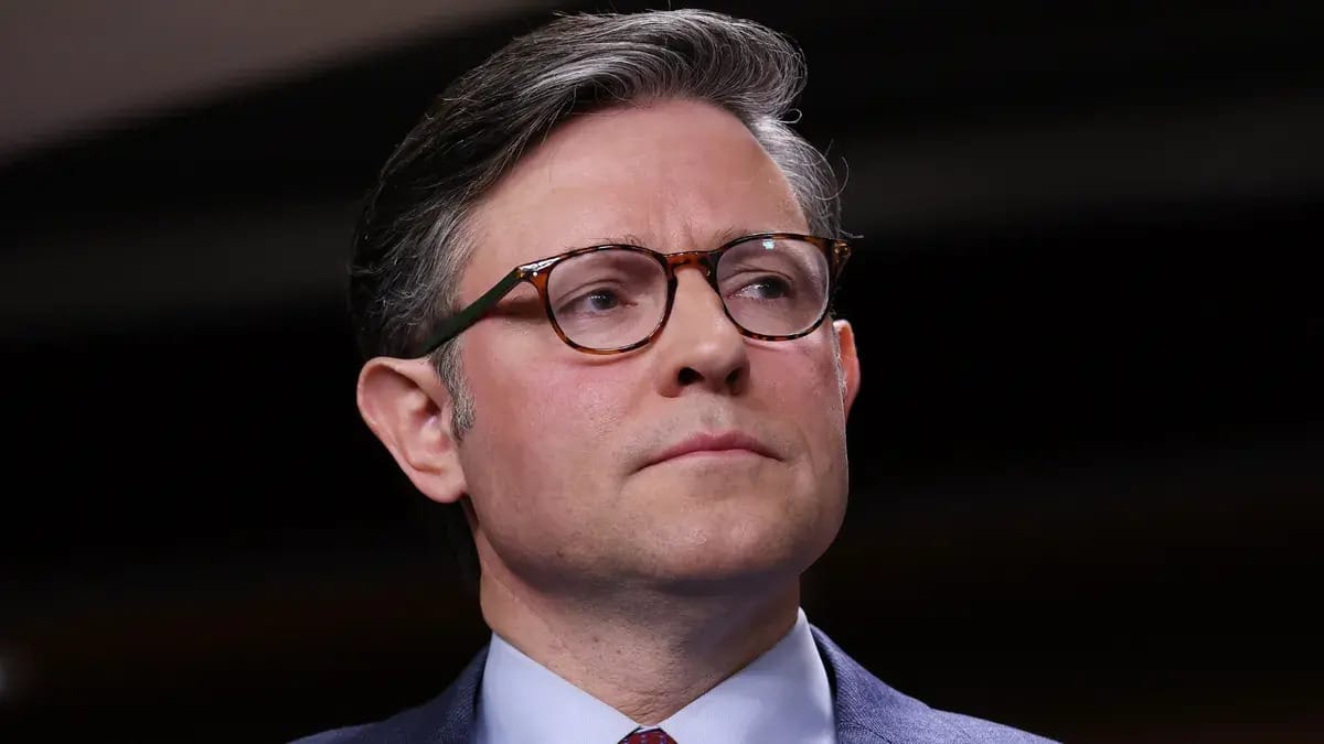 A white man wearing glasses is pictured looking to the right.