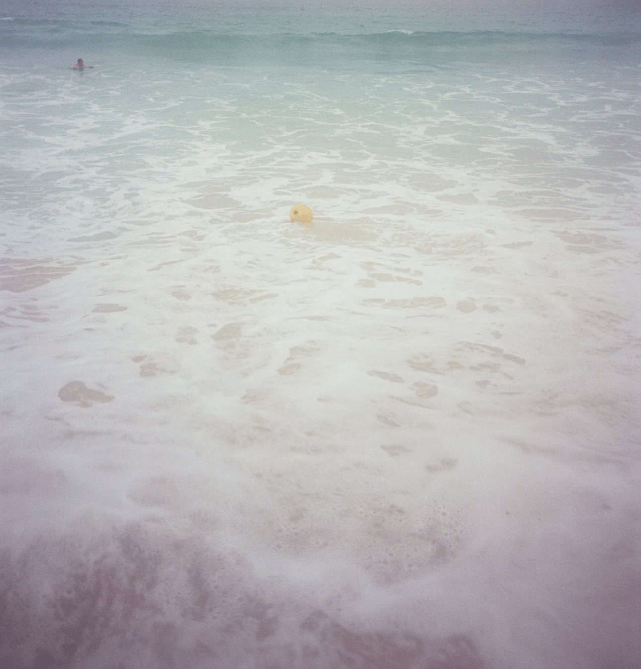 A yellow buoy floats in frothy surf.