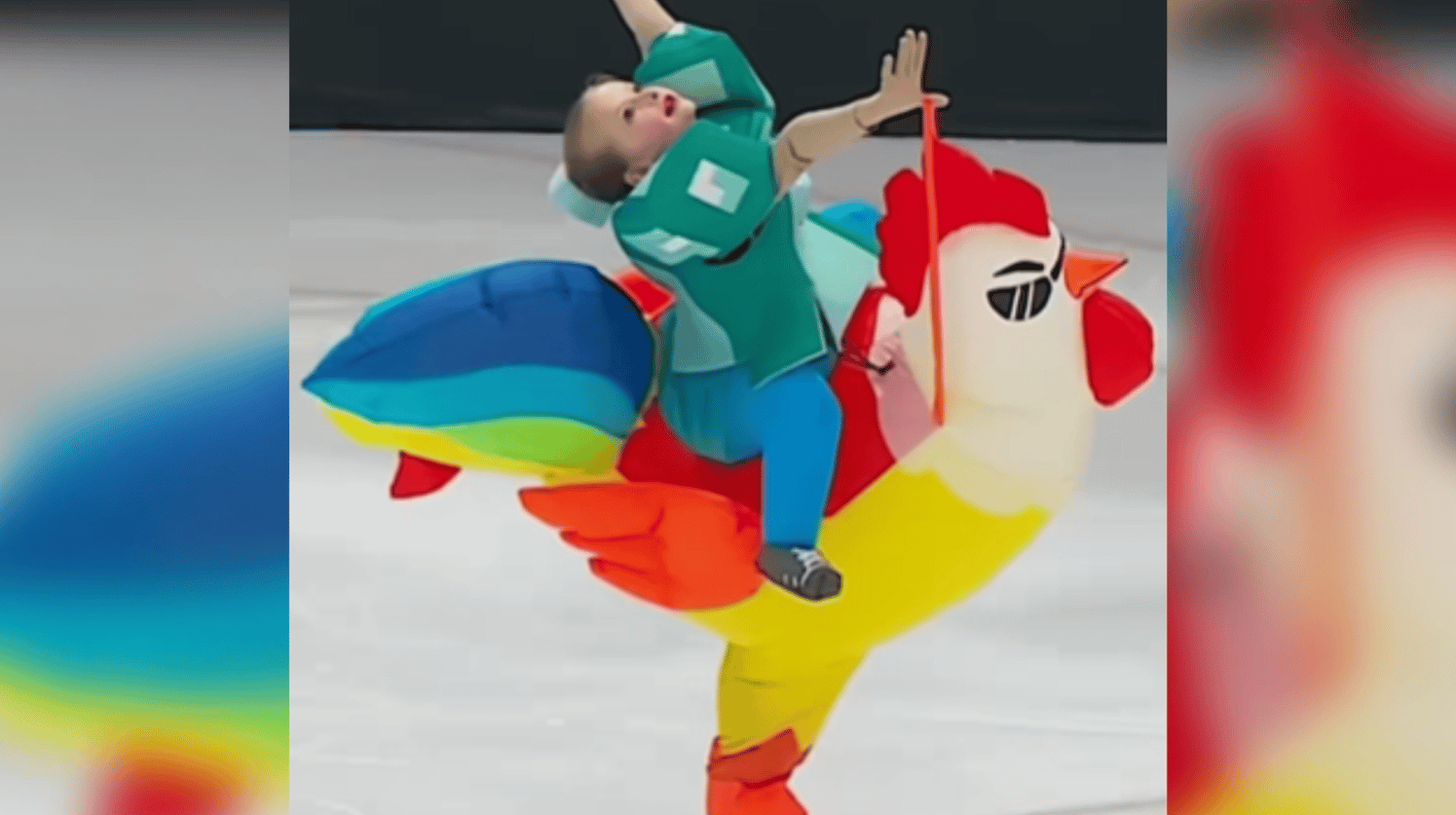 A little girl throws her arms into the air as she ice skates while wearing a chicken inflatable