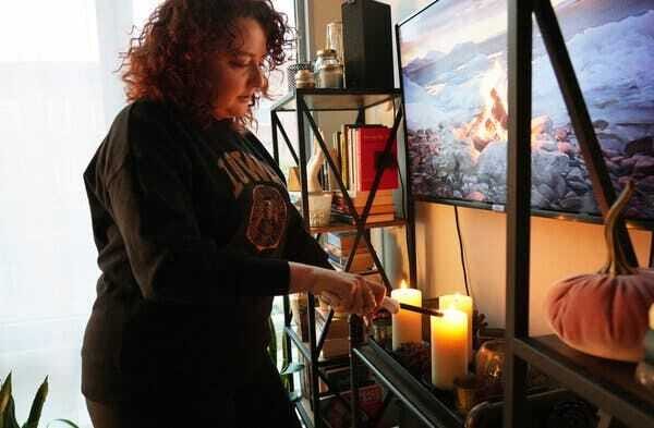 Ms. Kadlec, wearing a black sweatshirt that says “Iowa” in yellow lettering, lights several candles.