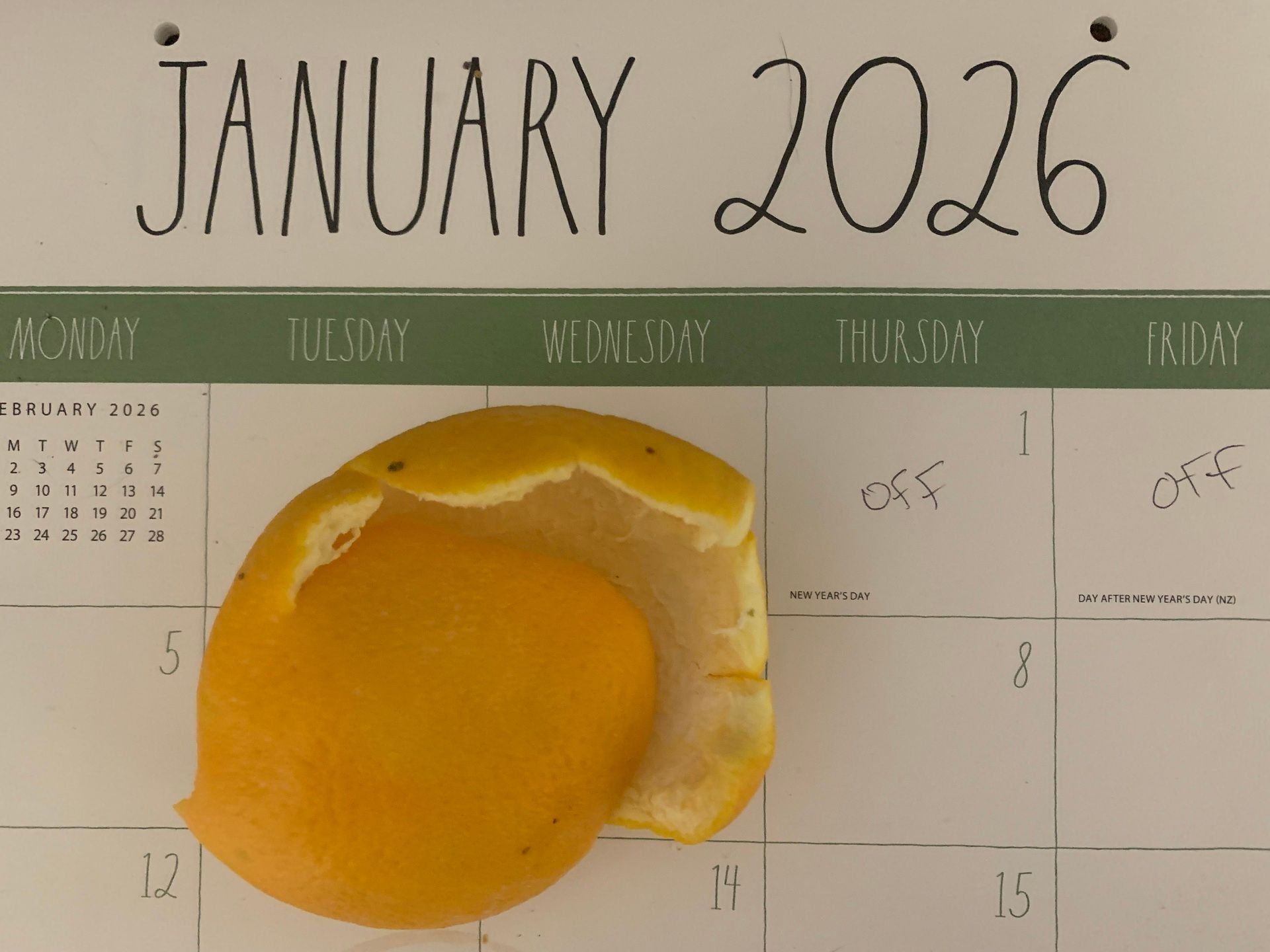 A photo of a deflated, empty orange peel sitting on a desk calendar that reads "JANUARY 2026" at the top.
