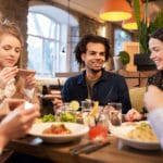 Group of friends sitting at table and eating together