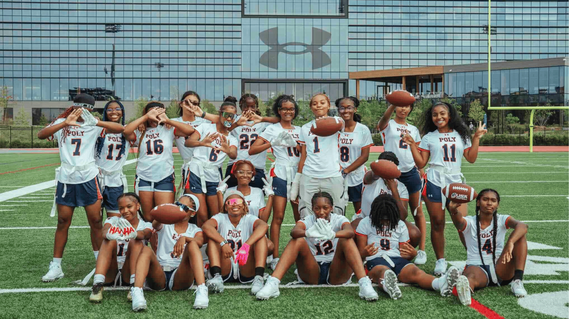A girls flag football team poses in front of the Under Armour building