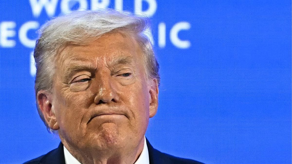 A white man wearing a black suit looks slightly to the right.