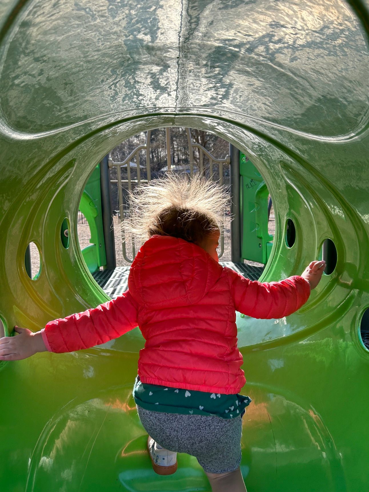 A child in a slide wit their hair sticking out straight