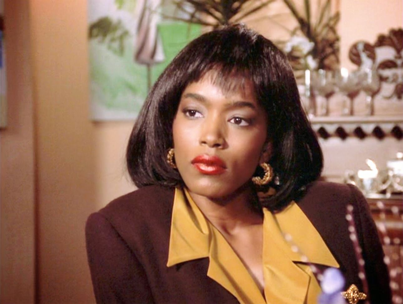 Screenshot of Angela Bassett in Boyz n the Hood, standing beside her son with a determined look, framed in a modest family home.