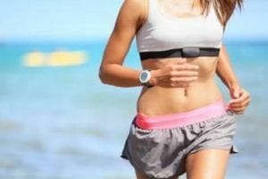 Woman running on the beach with GPS running watch