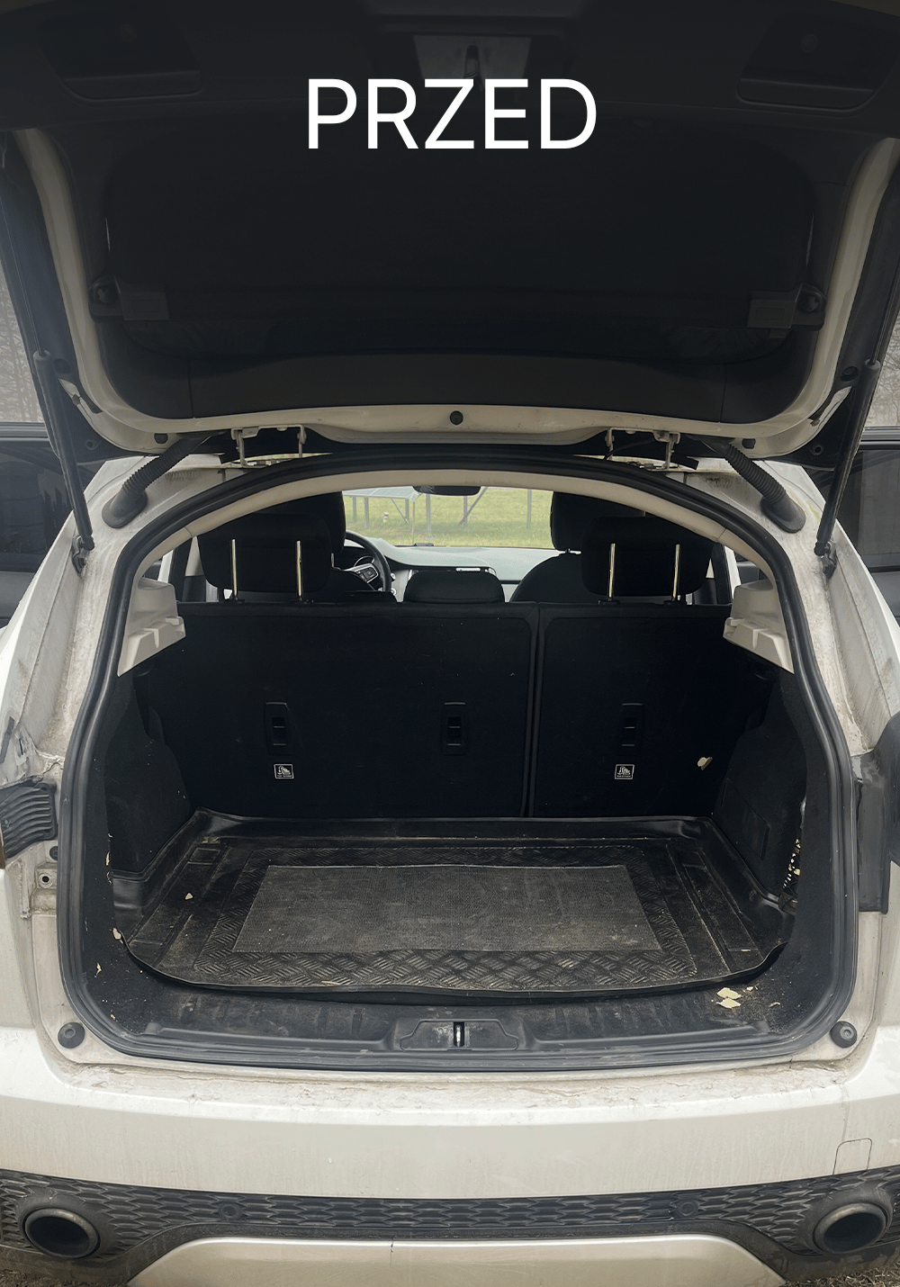 Zabrudzony bagażnik w Jaguarze przed czyszczeniem – brudna mata, kurz i zanieczyszczenia przy krawędziach przestrzeni ładunkowej, Chełmno, kujawsko-pomorskie