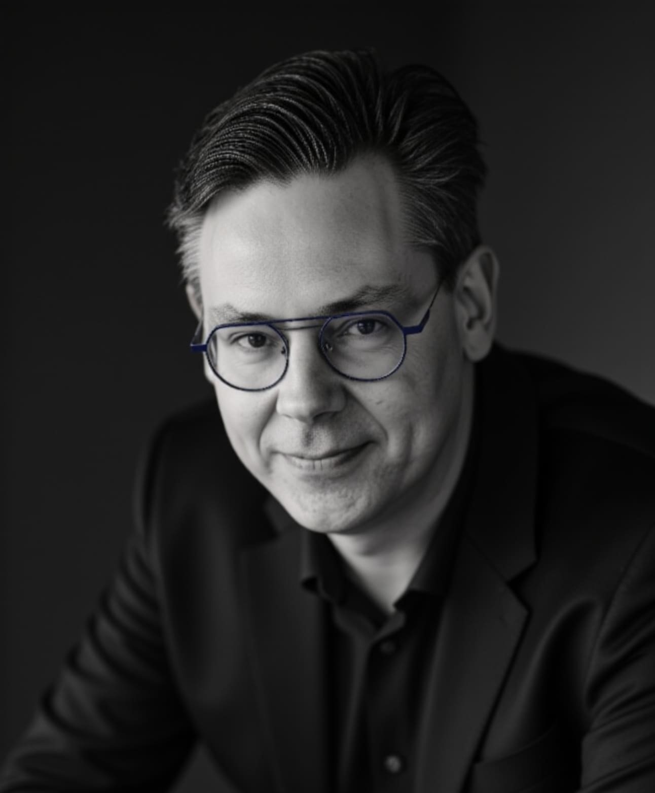 A headshot of a smiling middle aged man—Steven Claes, CHRO—with glasses, clean shaven, in a blazer and dress shirt