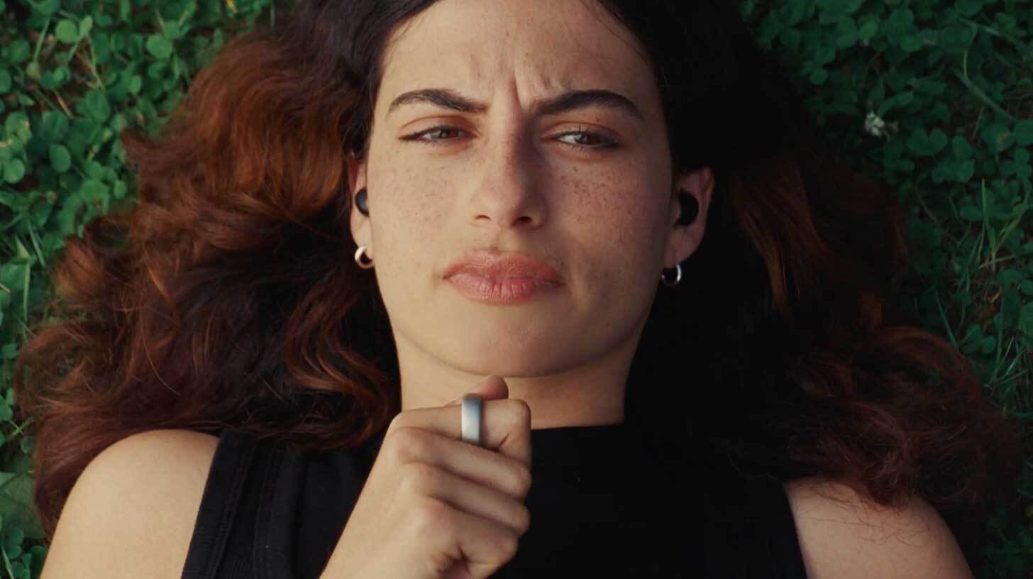 Naine lamab murul, kõrvades juhtmevabad kõrvaklapid. Ta kannab musta särki ning tema näol on tõsine ilme. Naise käes on sõrmus.